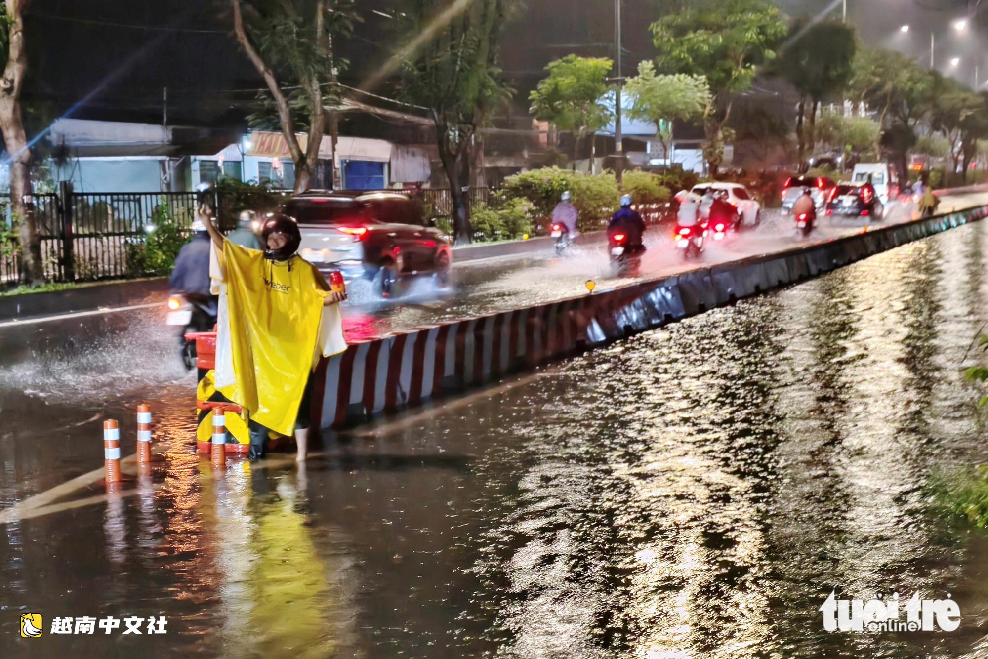 胡志明市男子夜晚涉水引導車輛避開積水路段