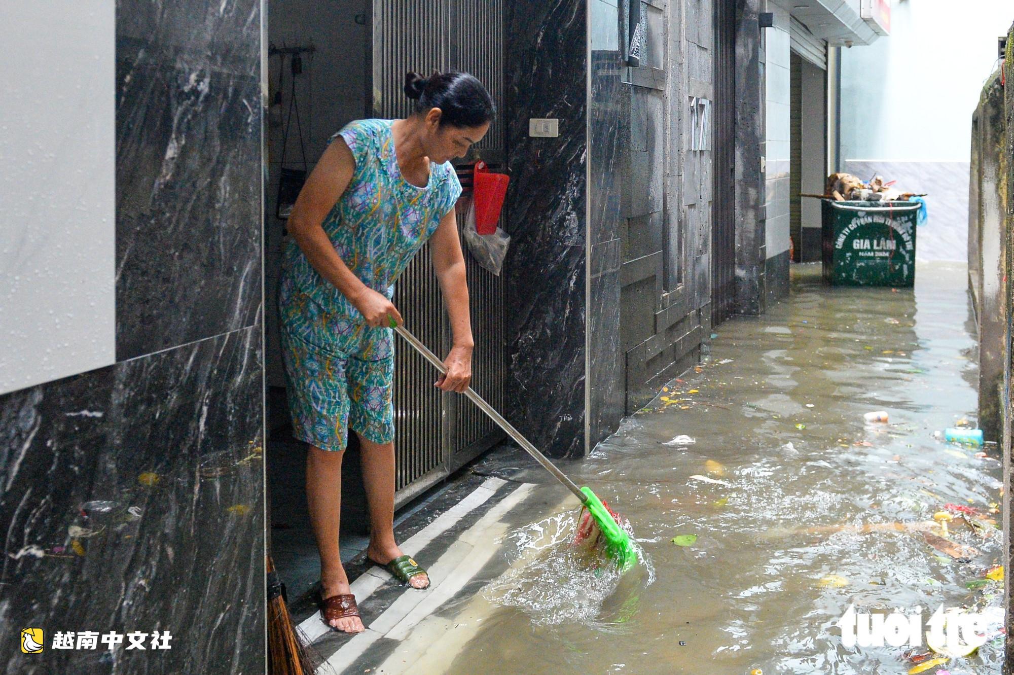 越南河內:每逢下雨就內澇的地方,居民用掃帚推垃圾、用木板擋水防漫進家中