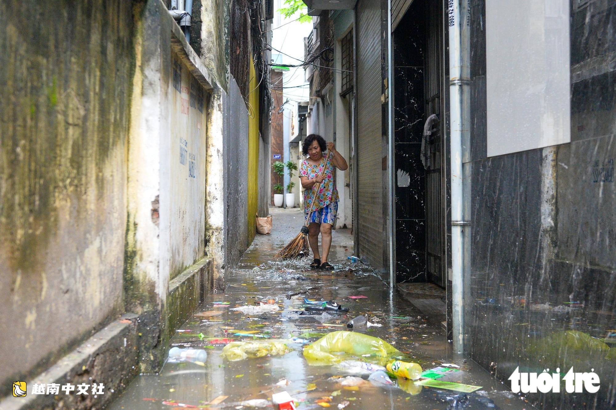 越南河內:每逢下雨就內澇的地方,居民用掃帚推垃圾、用木板擋水防漫進家中