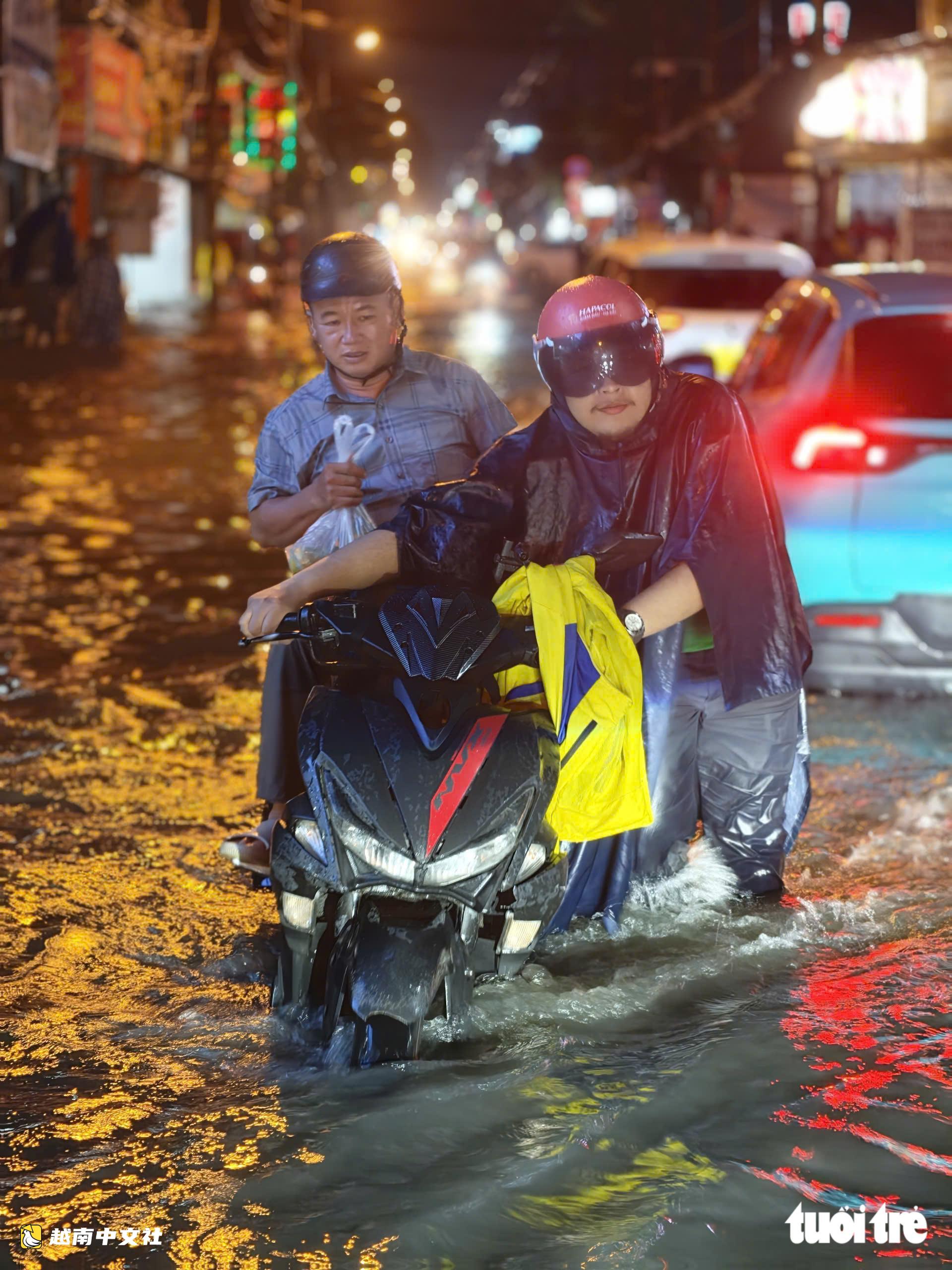 越南胡志明市:晚上22點,潘輝益路上摩托車成排熄火,民眾疲憊推車涉水回家