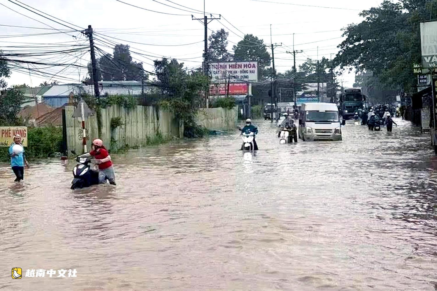 越南同奈大雨漲潮,民眾清晨蹚水上班