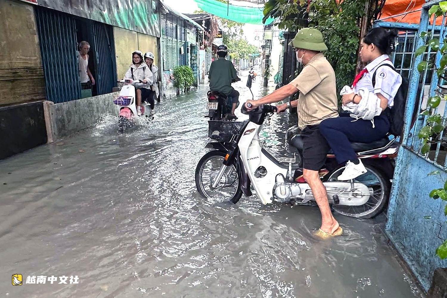 越南同奈大雨漲潮,民眾清晨蹚水上班