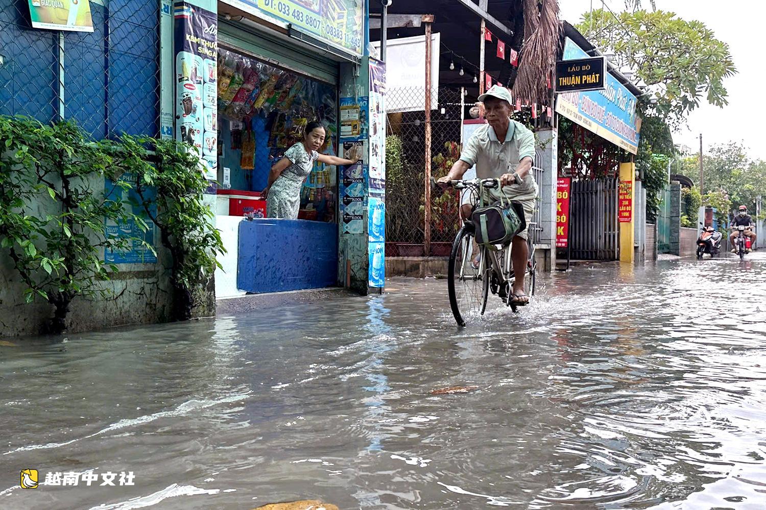 越南同奈大雨漲潮,民眾清晨蹚水上班