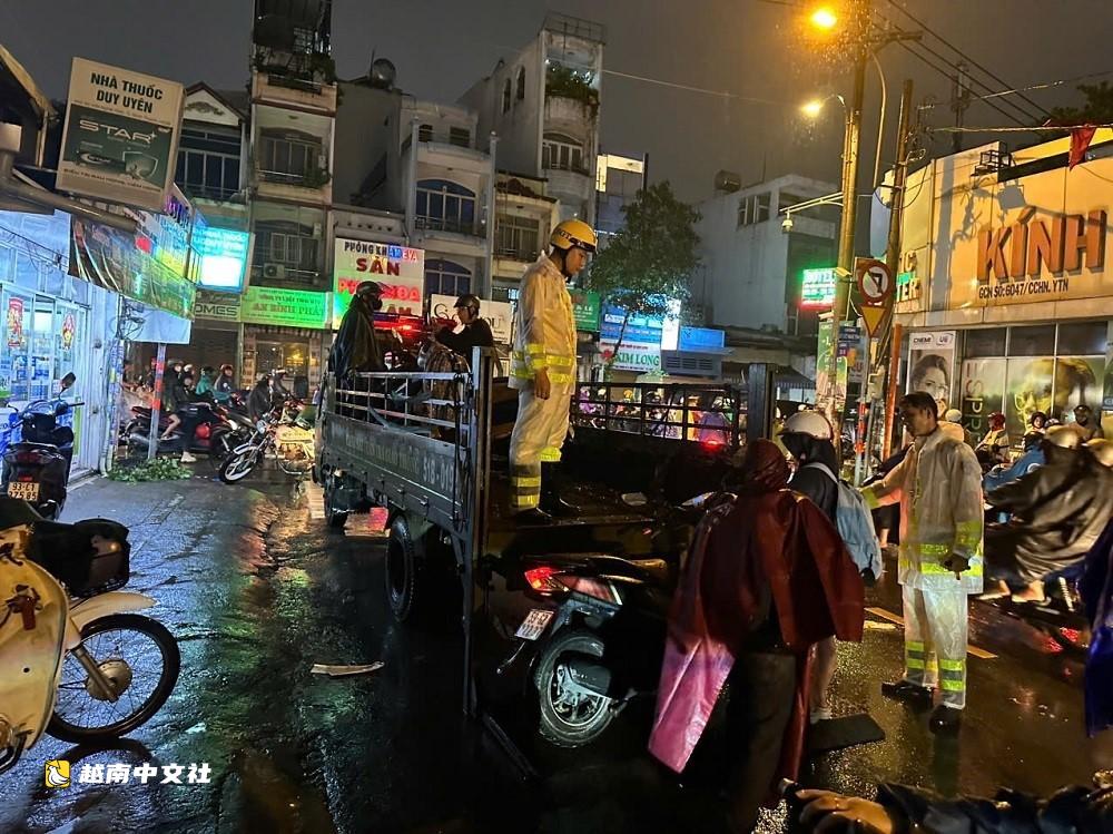 胡志明市交警冒雨分流，涉水幫民眾推摩托車過積水路段