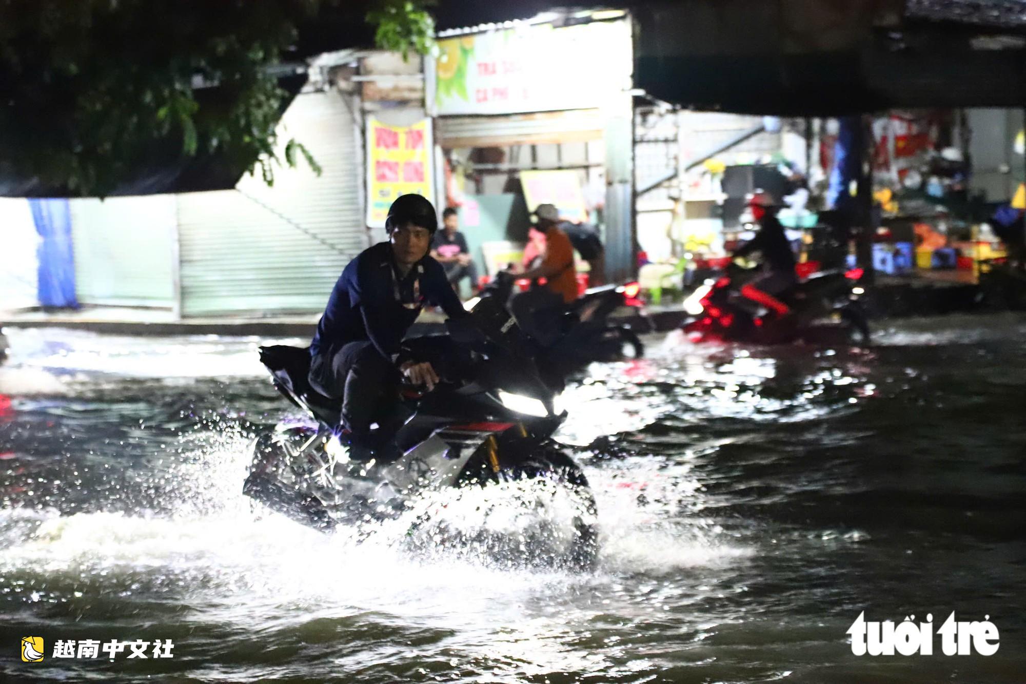 胡志明市通勇市場附近道路大雨後積水,民眾陷入坑洞摔倒