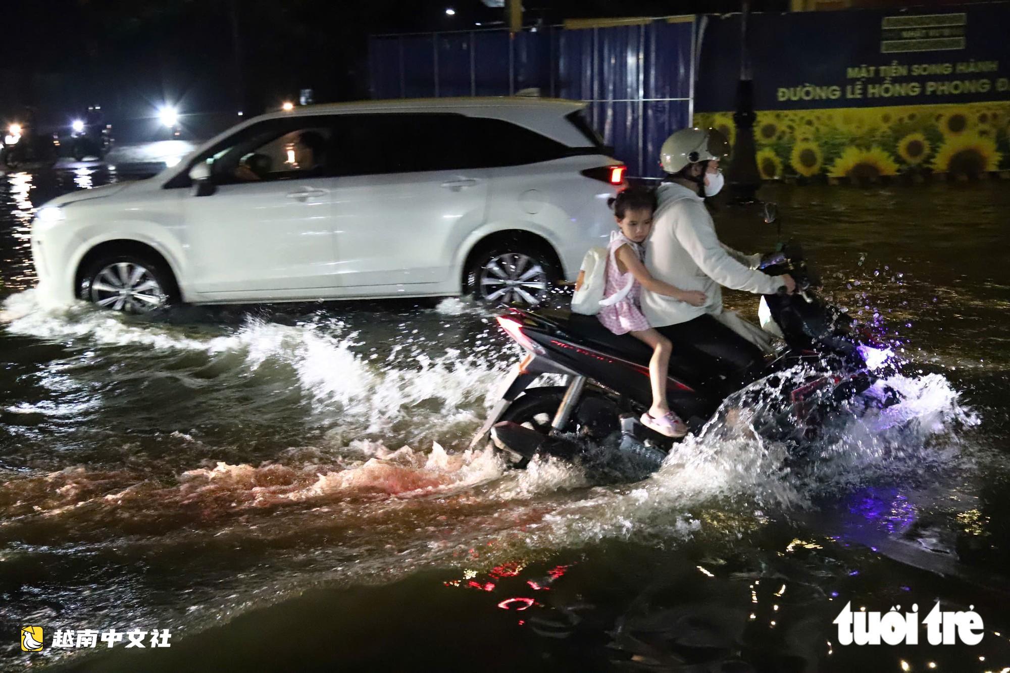 胡志明市通勇市場附近道路大雨後積水,民眾陷入坑洞摔倒