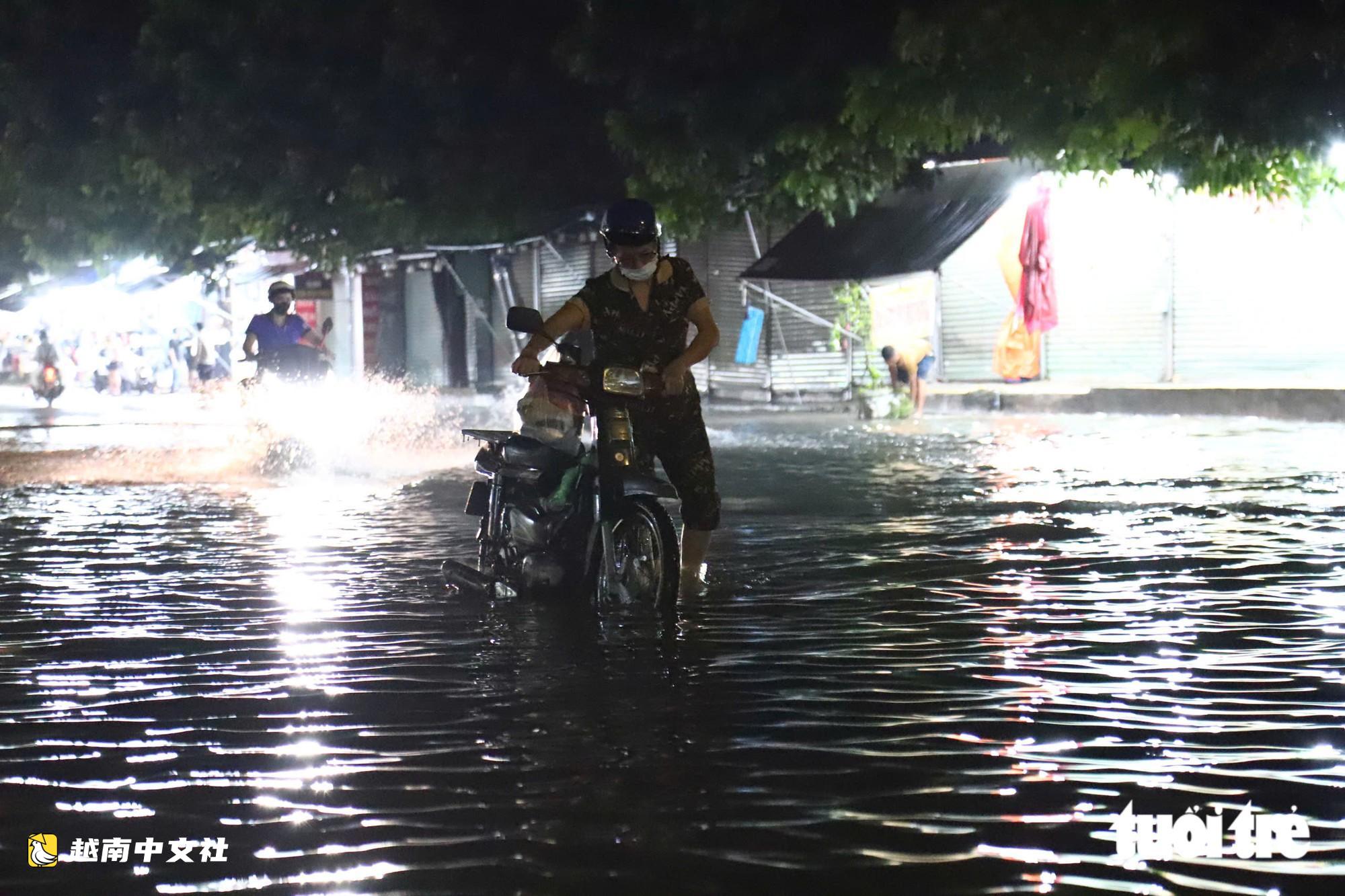 胡志明市通勇市場附近道路大雨後積水,民眾陷入坑洞摔倒