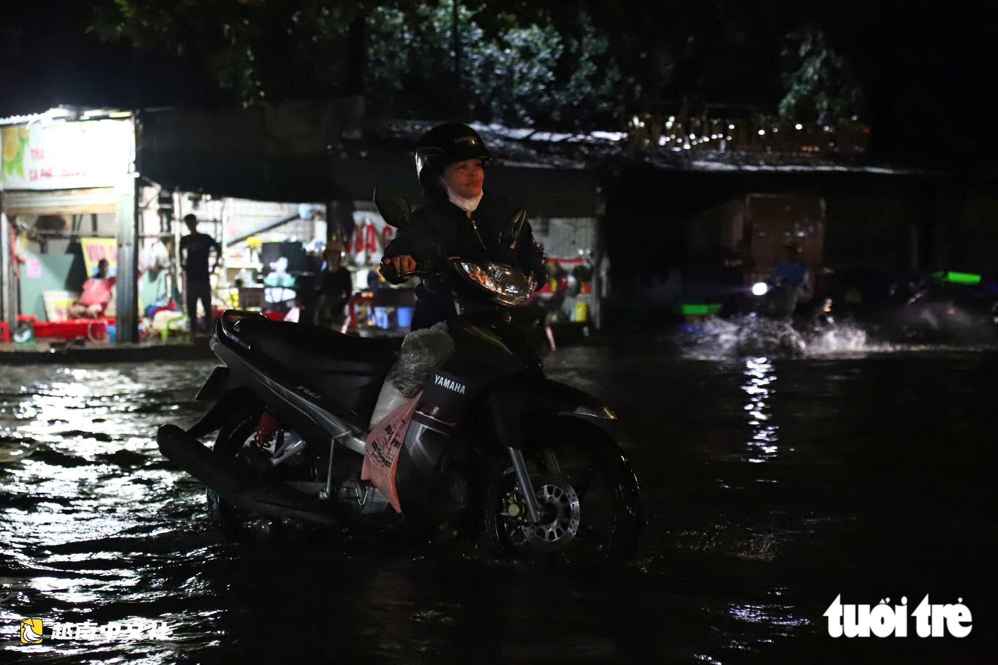 胡志明市通勇市場附近道路大雨後積水,民眾陷入坑洞摔倒