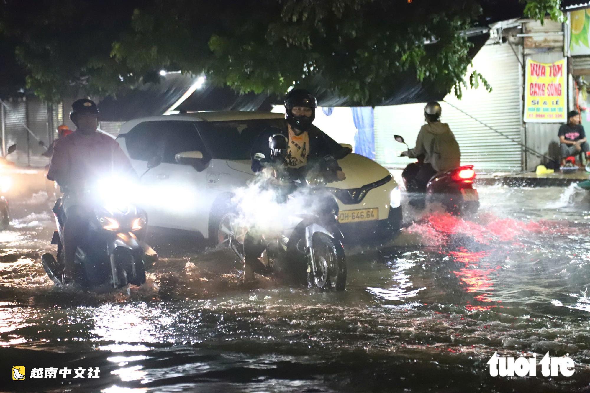 胡志明市通勇市場附近道路大雨後積水,民眾陷入坑洞摔倒