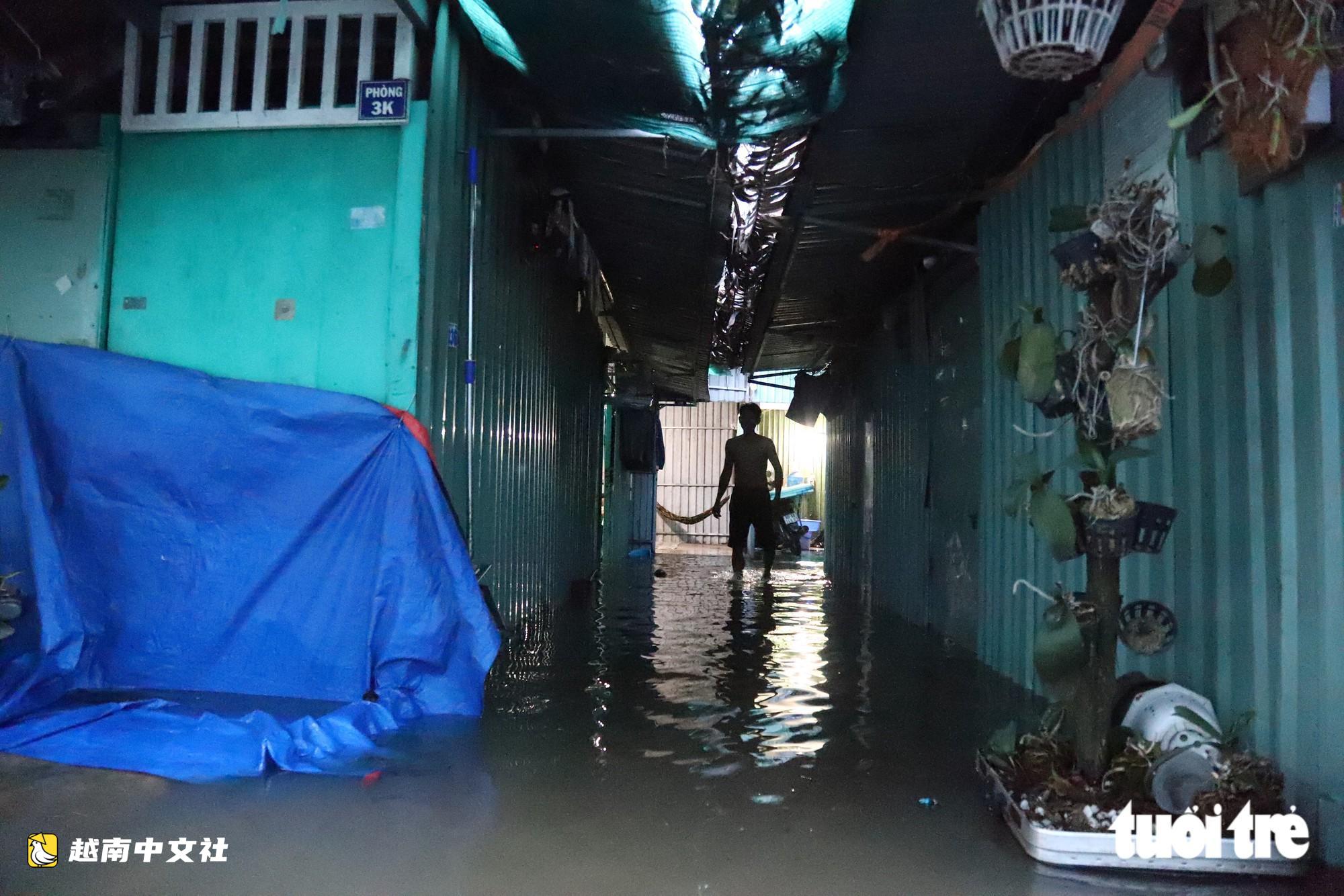 胡志明市潮水達峰,民眾在門前築‘堤’,兒童在潮水中游泳
