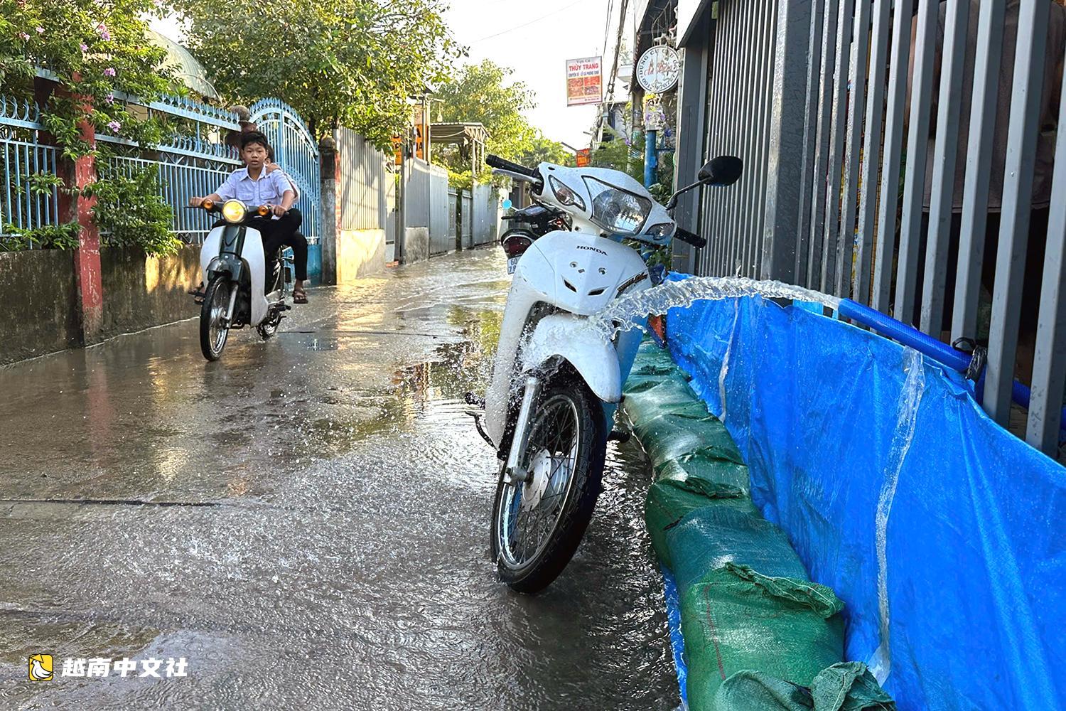 越南同奈河潮水上漲,低窪地區民眾蹚水出行