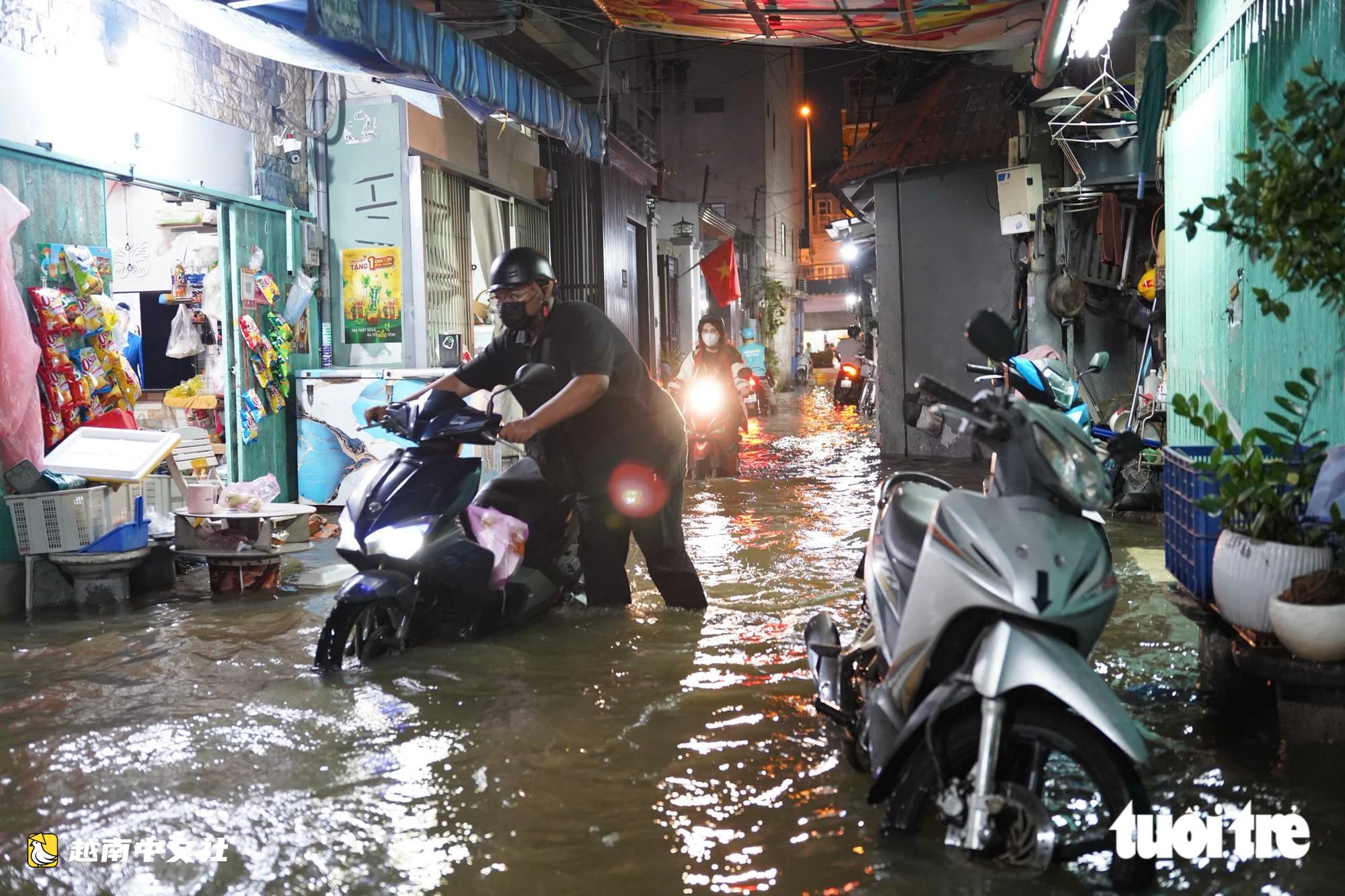 胡志明市潮水達峰,民眾在門前築‘堤’,兒童在潮水中游泳
