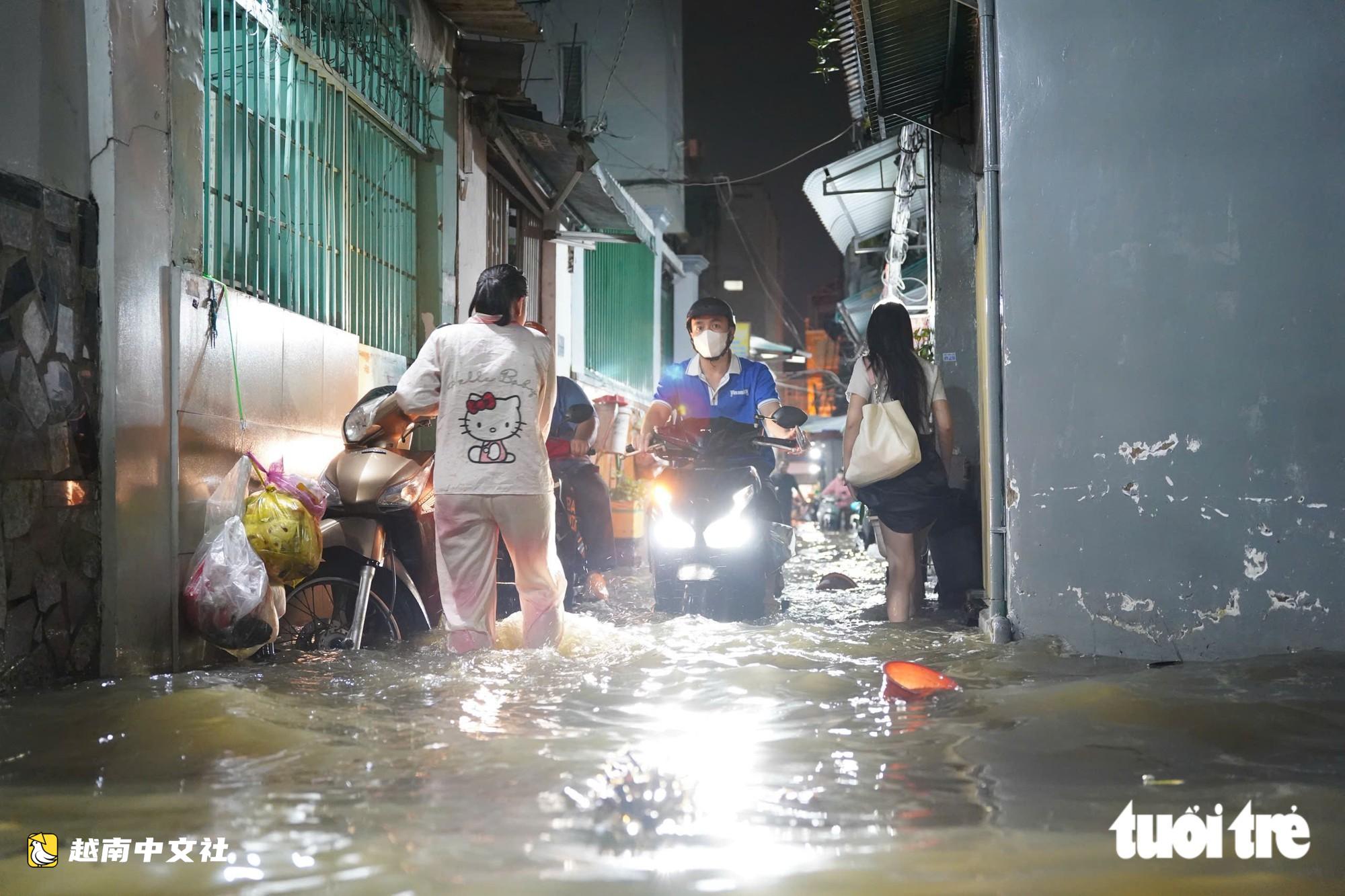 胡志明市潮水達峰,民眾在門前築‘堤’,兒童在潮水中游泳