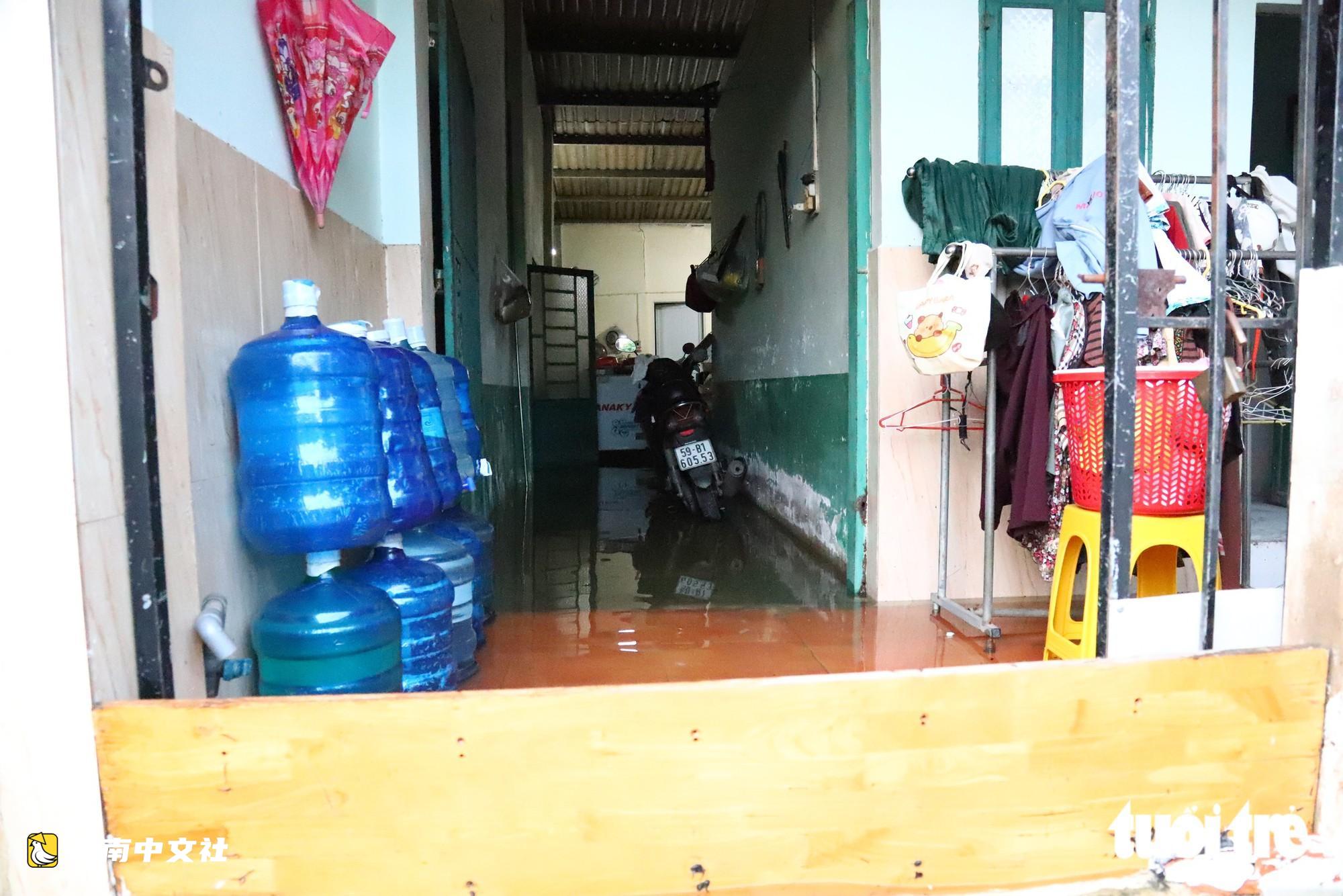 胡志明市潮水達峰,民眾在門前築‘堤’,兒童在潮水中游泳