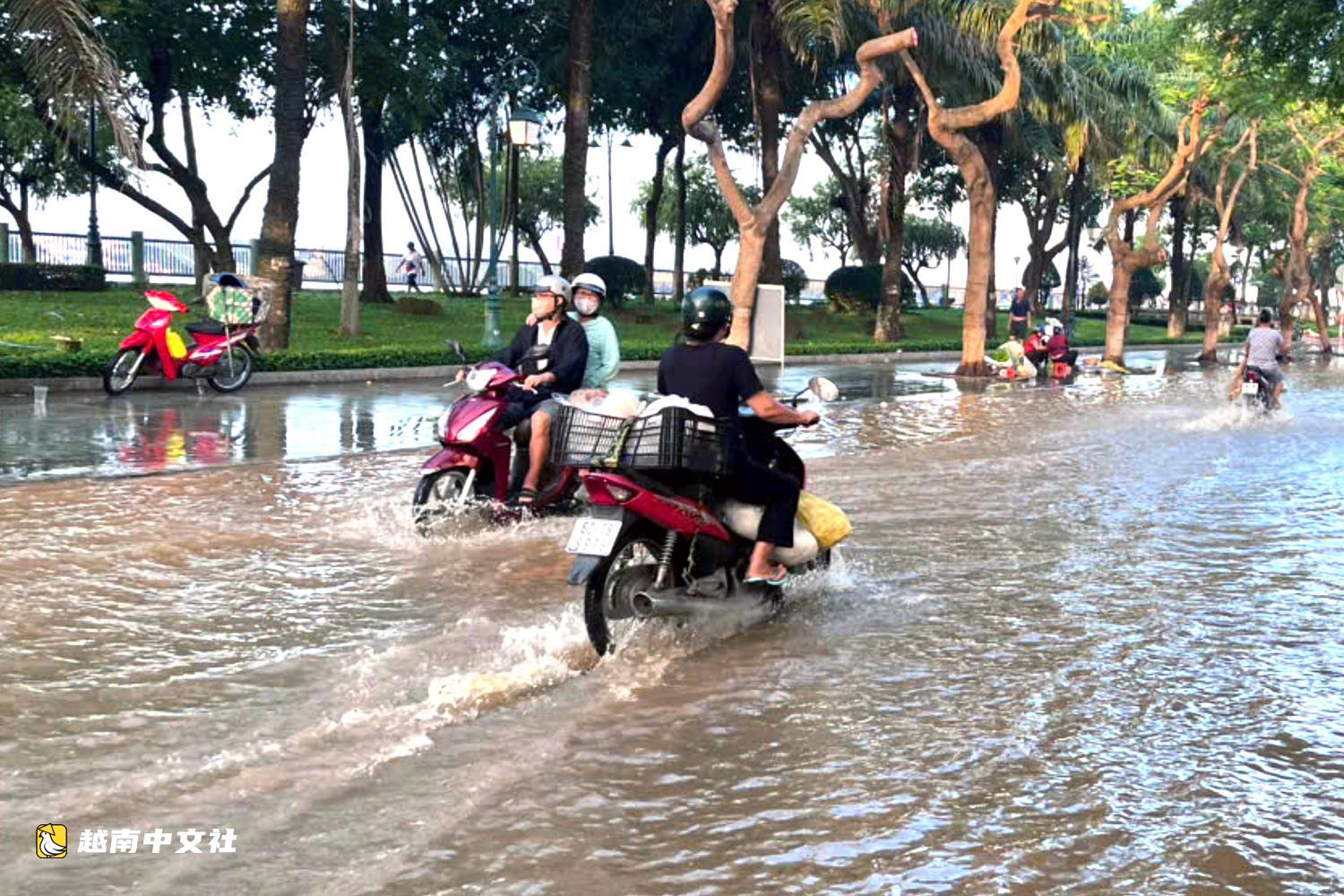 越南同奈河潮水上漲,低窪地區民眾蹚水出行