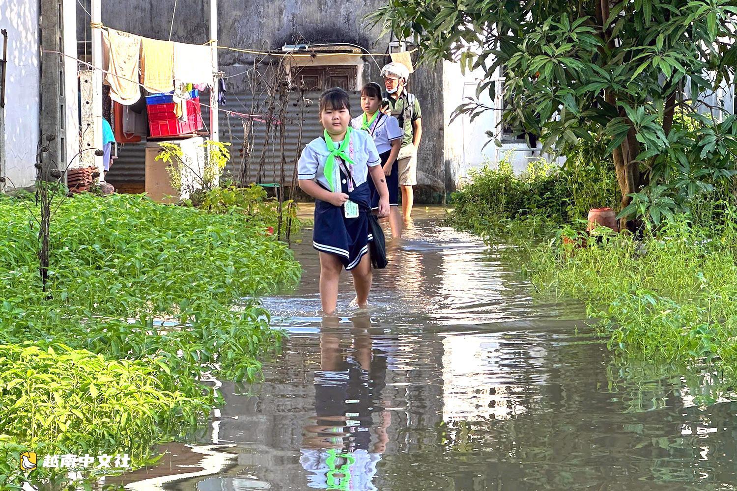 越南同奈河潮水上漲,低窪地區民眾蹚水出行