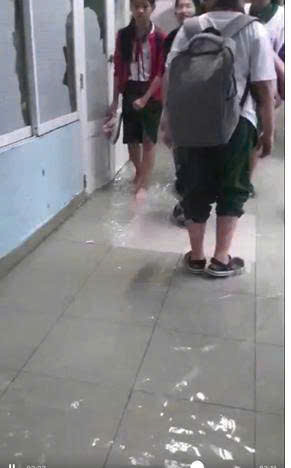 胡志明市一所学校每逢大雨就积水，老师们必须舀水