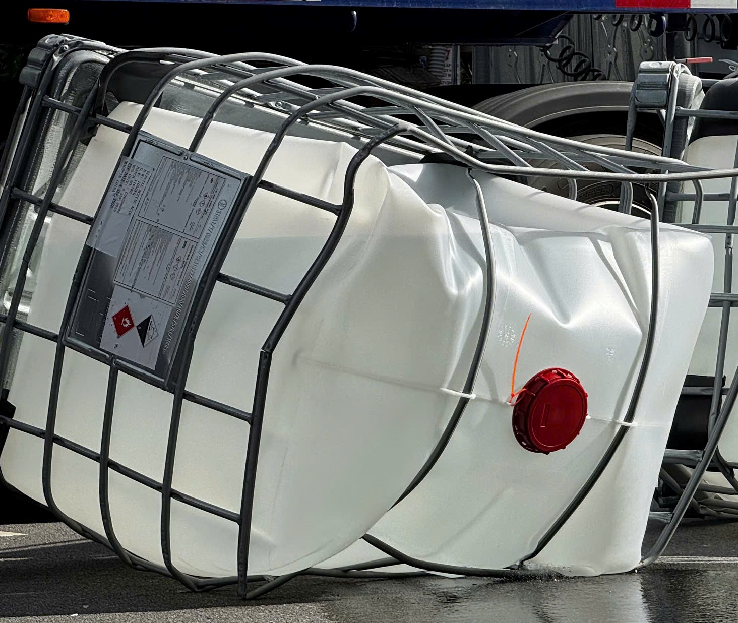 四个塑料桶装冰醋酸掉落街道，散发气味，居民感到恶心